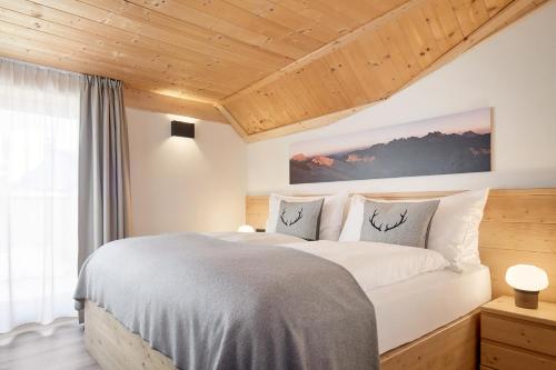 1 dormitorio con 1 cama grande y techo de madera en Residence Settsass, en Colfosco