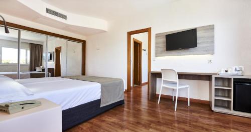 a hotel room with a bed and a desk with a tv at Globales Cala Viñas Adults Only 16+ in Cala Vinyes