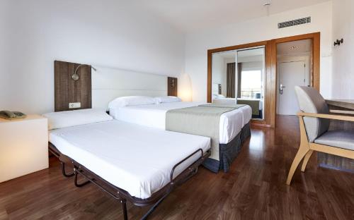 a hotel room with two beds and a chair at Globales Cala Viñas Adults Only 16+ in Cala Vinyes