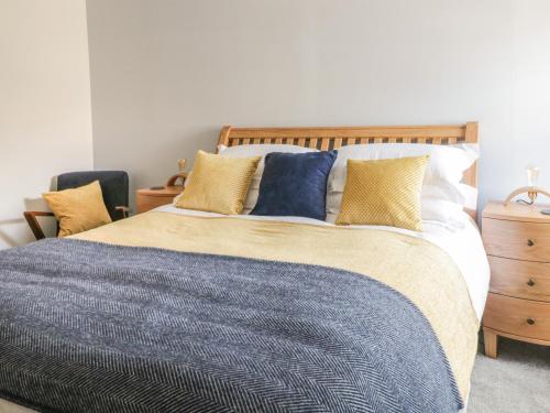 a bedroom with a large bed with blue and yellow pillows at Sunny Mount Cottage in Skipton