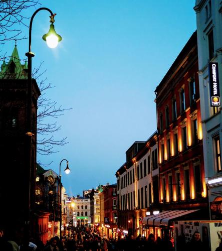 a crowd of people walking down a city street at night at First Hotel Millennium in Oslo