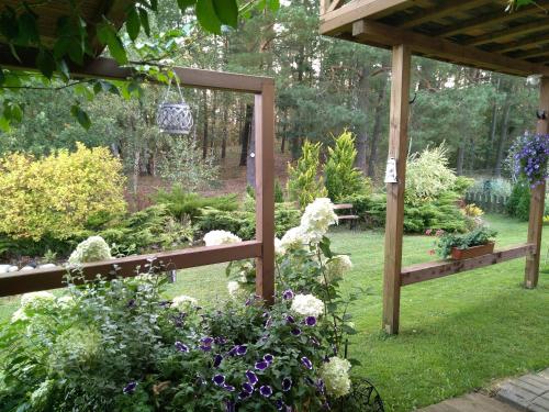 a garden with a wooden pergola and some flowers at Szumi Las in Szumles Królewski