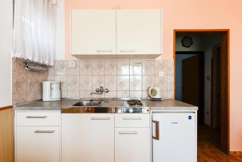 a kitchen with white cabinets and a sink at Villa Fontana in Starigrad-Paklenica