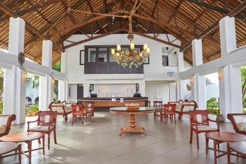 Habitación grande con mesas, sillas y lámpara de araña. en Jacaranda Indian Ocean Beach Resort en Diani Beach