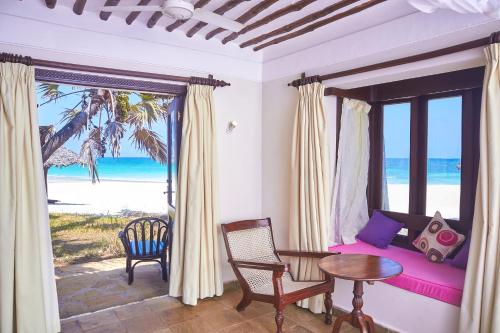 a room with a bedroom with a bed and a table at Jacaranda Indian Ocean Beach Resort in Diani Beach