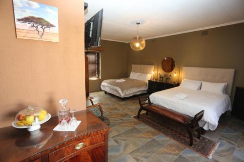 a bedroom with two beds and a table with a bowl of fruit at Prospectors Inn in Lüderitz