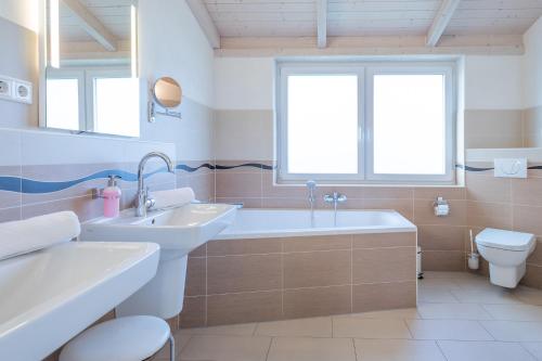 ein Badezimmer mit zwei Waschbecken, einer Badewanne und einem WC in der Unterkunft Ferienhaus Süderoog in Dagebüll
