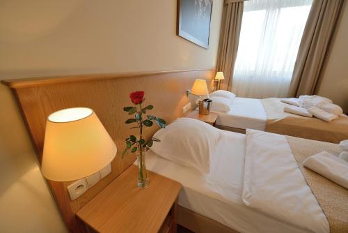 a hotel room with two beds and a vase with a flower at Hotel Alpejski in Polanica-Zdrój