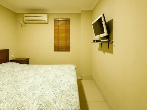 Rhiz Guest House Tebet في جاكرتا: غرفة نوم مع سرير وتلفزيون على الحائط