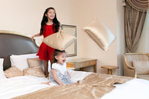 two little girls jumping on a bed with a pillow at Kempinski Hotel & Residences Palm Jumeirah in Dubai