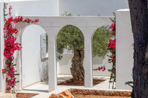 a white building with two archways with pink flowers at Villa Magdala in Portopetro