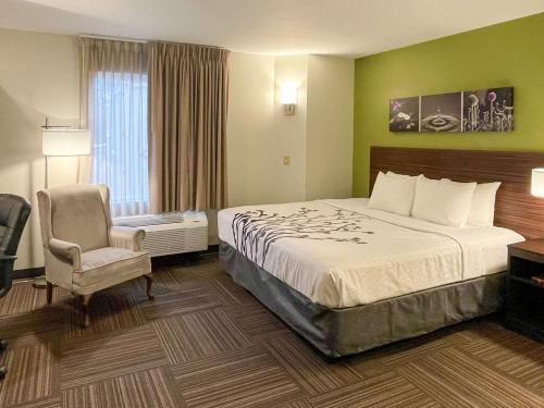 a hotel room with a bed and a chair at Sleep Inn in Antigo
