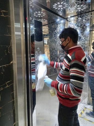 a man in striped shirt cleaning a glass window at Hotel Airlift at Delhi Airport in New Delhi