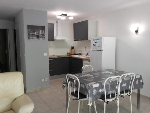 une cuisine avec une table avec des chaises et un réfrigérateur dans l'établissement T3 au bord de mer, à Saint-Cyr-sur-Mer