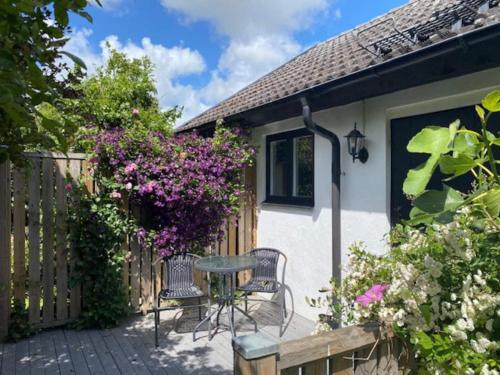 a cottage with a table and chairs and flowers at Mysigt gästhus med cykelavstånd till havet! in Skivarp