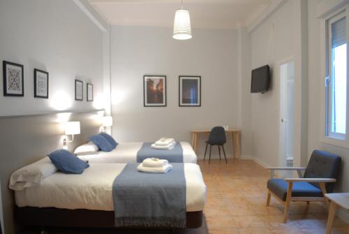 una camera con due letti e un tavolo con sedie di La Perla Granada Suites a Granada
