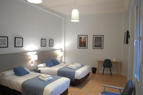 a hotel room with two beds and a desk at La Perla Granada Suites in Granada