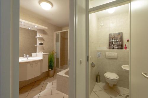 een badkamer met een toilet, een wastafel en een bad bij Wijde Blick appartement 211 - Callantsoog in Callantsoog