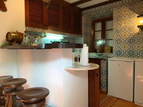 a kitchen with a counter with stools and a refrigerator at Stone House - Sete Cidades in Sete Cidades