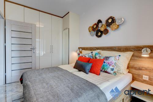 a bedroom with a large bed with colorful pillows at Apartament KORAL Gardenia Seaside 2 - Aprent in Dziwnów