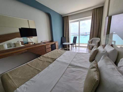 a hotel room with a large bed with a view of the ocean at Water's Edge Hotel in Birżebbuġa