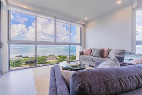 a living room with a couch and a large window at Azure Beach Residences in Palm-Eagle Beach