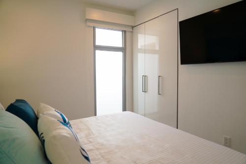 a bedroom with a bed and a flat screen tv at Azure Beach Residences in Palm-Eagle Beach