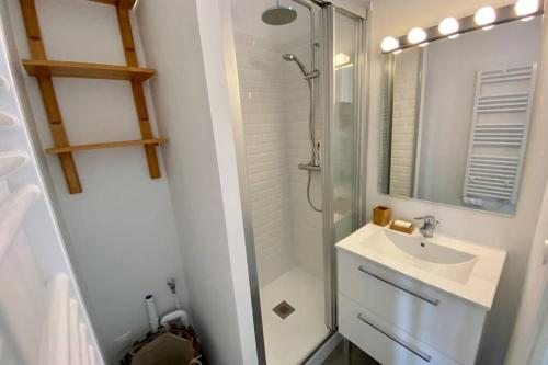 une salle de bain blanche avec un lavabo et une douche dans l'établissement EVENTAIL agréable 2 pièces proche mer et ville, à Cabourg