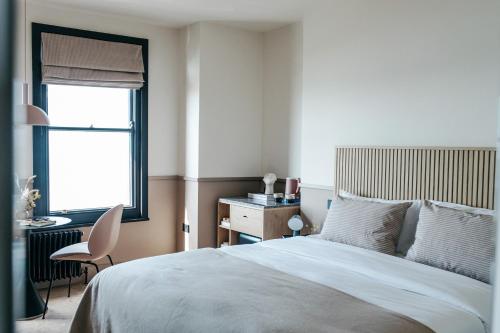 a bedroom with a bed and a desk and a window at Port Hotel in Eastbourne