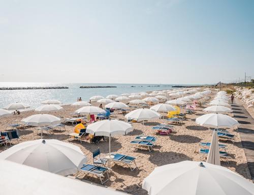 a group of umbrellas and chairs on a beach at Natural Village Resort in Porto Potenza Picena