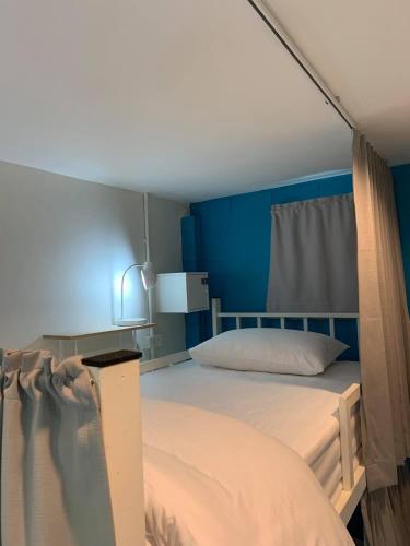 a bedroom with a bed with a blue wall at Naisang Hostel in Chumphon