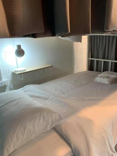 a large white bed in a room with a lamp at Naisang Hostel in Chumphon