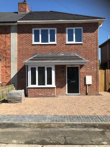 une maison en briques avec une porte et des fenêtres noires dans l'établissement Modern Comfort House On Eamont RD, à Stockton-on-Tees