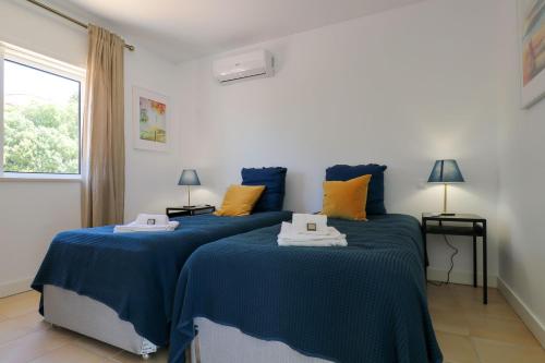 Duas camas num quarto com almofadas azuis e amarelas em LovelyStay - Divine 3BDR Duplex House w/ Pool & Garden em Patroves