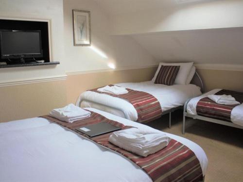 a hotel room with three beds and a tv at Seagull Hotel in Blackpool