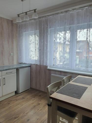 Una cocina con mesa y sillas y ventanas. en Hotel Schneider Apartaments, en Langenhagen