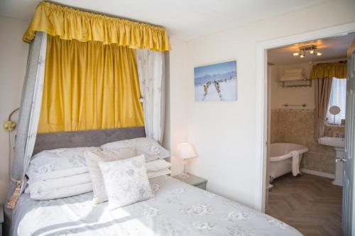 ケトルウェルにあるThe Cottage Tea Room B&Bのベッドルーム(白いベッド1台、黄色い窓付)