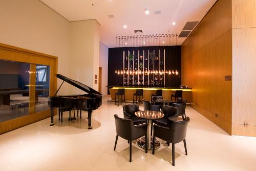 a dining room with a piano and a bar at Hotel Araucaria Flat in Araraquara