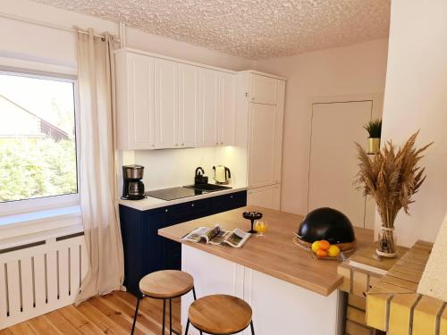 a kitchen with white cabinets and a counter with stools at Baltic House in Kopalino