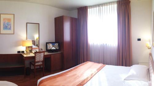 a hotel room with a bed and a desk and a window at Hotel Marconi in Padova