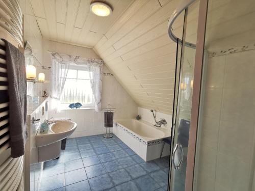 W łazience znajduje się umywalka, wanna i prysznic. w obiekcie Ferienhaus Scharhörn w mieście Horumersiel