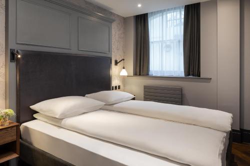 two white beds in a bedroom with a window at Hapimag Apartments London in London