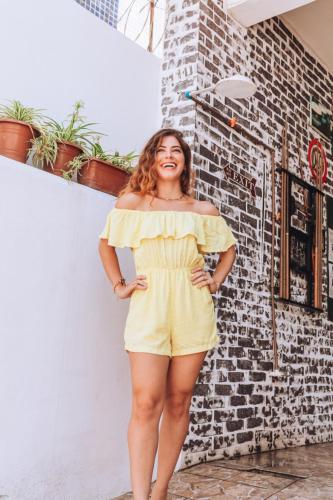 a woman in a yellow dress standing next to a brick wall at Hostel Barra in Salvador