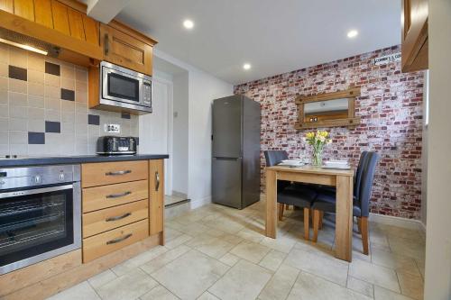 a kitchen with a table and a brick wall at Host & Stay - Cummins & Goings Cottage in Barnard Castle