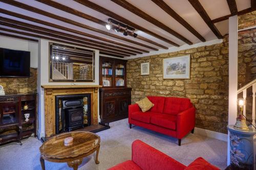 a living room with a red couch and a fireplace at Fab 2 Bed Cotswolds Cottage with Private Courtyard 