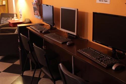 a desk with three computer monitors and a keyboard at Hostel New York in Barcelona