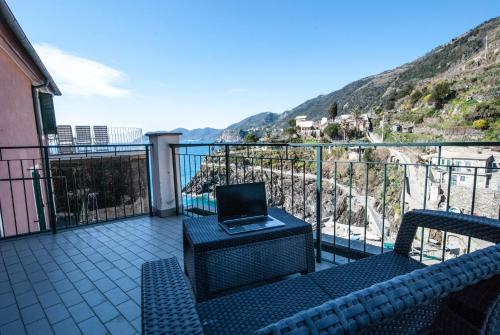 a balcony with a laptop computer sitting on a chair at Luxury Seaview Apartments Manarola by Arbaspàa in Manarola