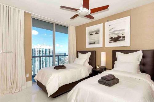 two beds in a bedroom with a large window at Icon Brickell -LUX 2 Bedroom with City & Bayview in Miami