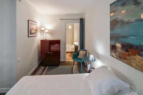une chambre avec un lit blanc et une chaise bleue dans l'établissement Appartement de la Tour - Welkeys, à Paris