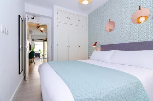a bedroom with a white bed and a blue wall at Maestranza Beach by Sol Maestranza in Málaga